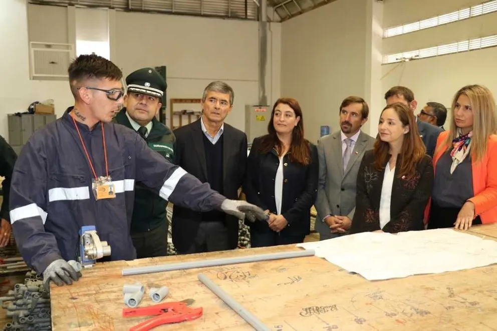 Juliano Marcos (i), una de las personas que se capacita y trabaja en el penal, explica a las autoridades el trabajo que realiza preparando redes de cañería para el agua que después ECOMAC utiliza en la construcción de viviendas.