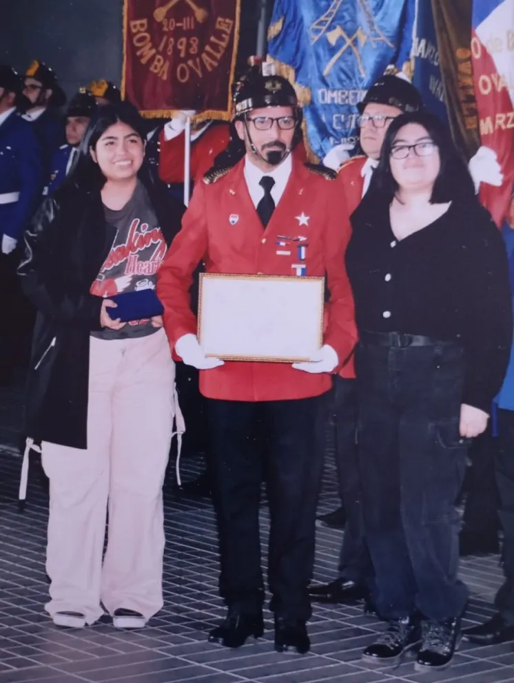Luis López junto a sus hijas, Constanza y María, durante la ceremonia en la que recibió un reconocimiento por sus 30 años de servicio en Bomberos.